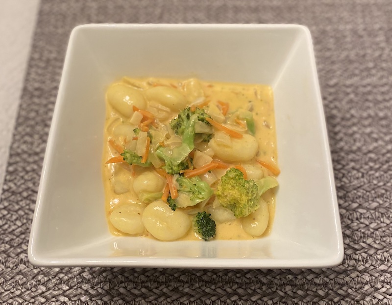 white bowl containing broccoli cheddar gnocchi meal
